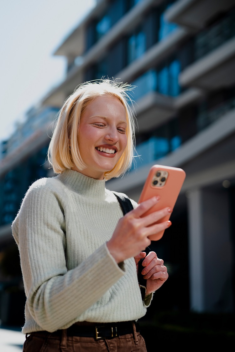 Happy,Girl,Walking,On,The,Street,Checking,Phone.,Beautiful,Blonde